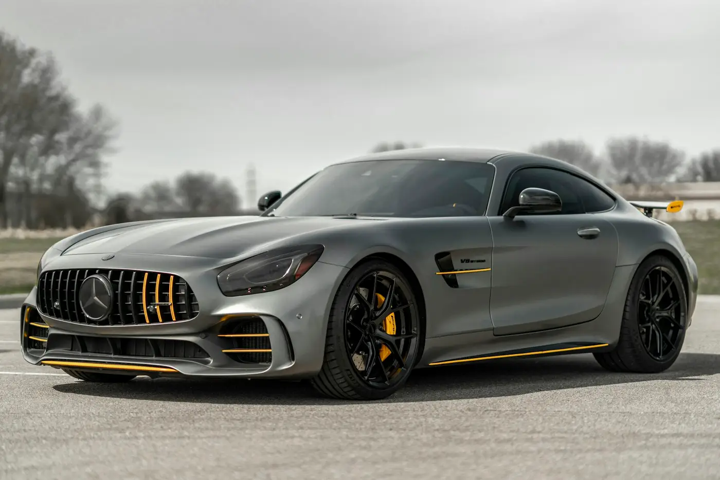 מרצדס-AMG GT קופה בגוון אפור מט, חונה במגרש פתוח ושטוח, מבט קדמי-צדדי