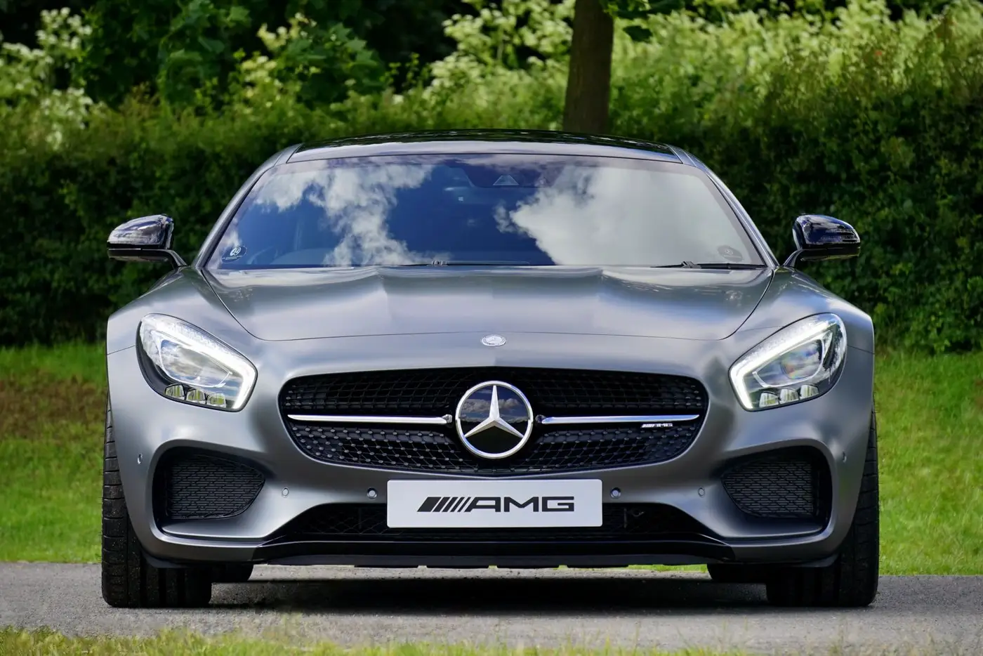 מרצדס-AMG GT כסופה במבט חזיתי ישר, עומדת על דשא עם עצים ברקע